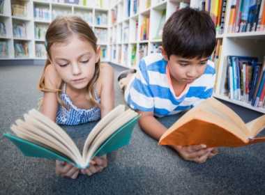 Copii care citesc cărți într-o bibliotecă