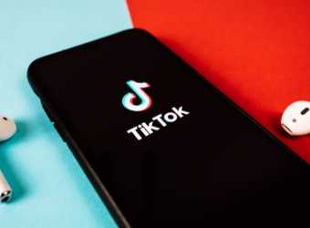 Telefon cu aplicația TikTok și căști wireless