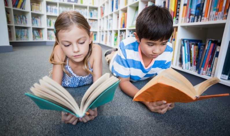 Copii care citesc cărți într-o bibliotecă